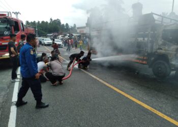 Personil Damkar Padang Pariaman tengah berusaha memadamkan truk ekspedisi yang terbakar di Kayu Tanam