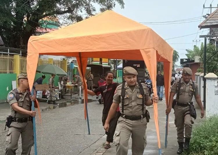 Petugas Satpol PP Padang menertibkan barang PKL yang berjualan di fasilitas umum, Senin (31/10/2022).