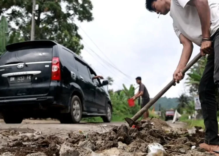 Warga di Tanah Datar berinisiatif menimbun jalan yang berlubang |(foto: Antara)