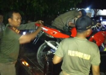 Petugas mengangkut motor pembalap liar di Jalan Khatib Sulaiman Padang, Jumat (29/12).