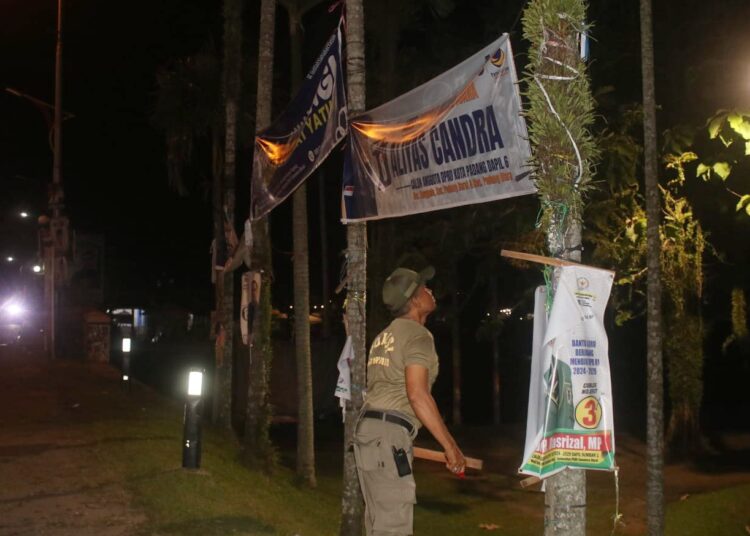 Satpol PP Padang menertibkan reklame dan alat peraga kampanye (APK) yang terpasang di lokasi terlarang di Kota Padang, Senin (22/1/24).