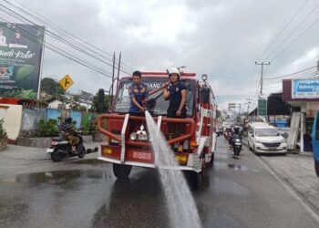 Damkar Kota Padang Panjang membersihkan abu vulkanik yang menutupi jalan, Jumat (5/1).