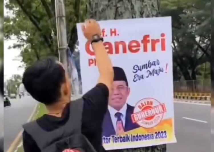 Aksi pegiat lingkungan Gerakan Selamatkan Pohon mencopot poster politikus di sebuah jalan di Kota Padang.