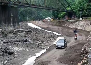 Kendaraan nekat melintasi jalan Lembah Anai pasca diterjang banjir bandang.