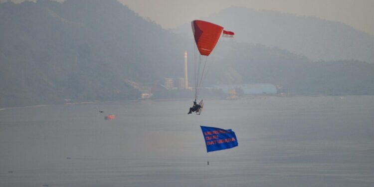 Bendera merah putih dan spanduk bertuliskan "Merdeka dari Batubara" tampak berkibar di sekitar PLTU Teluk Sirih dan sepanjang pesisir pantai Kota Padang pada Minggu (18/8).