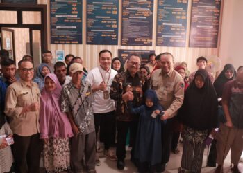 Pj Wali Kota Payakumbuh menyerahkan bansos kepada ratusan KK dan anak sekolah.