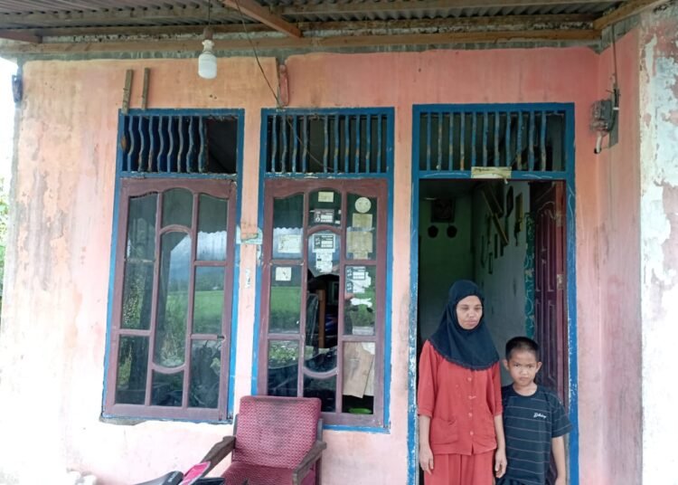 Nel Ardani dan anaknya berdiri di pintu rumahnya di Kampung Asam Kamba, Nagari Asam Kamba Pasar Baru, Kecamatan Bayang, Pesisir Selatan, Senin (28/4). Foto: IST