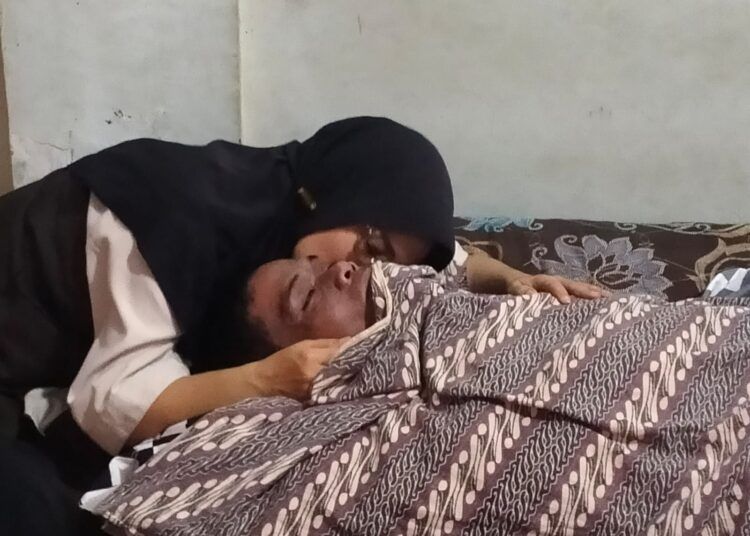 Mariza memeluk suaminya yang meninggal dunia akibat gantung diri di dalam rumah mereka di Jalan S. Parman Nomor 99, Jorong Jati, Nagari Baringin, Kecamatan Lima Kaum, pada Kamis (16/7/2026) sekitar pukul 12.30 WIB. Foto: Polsek Lima Kaum