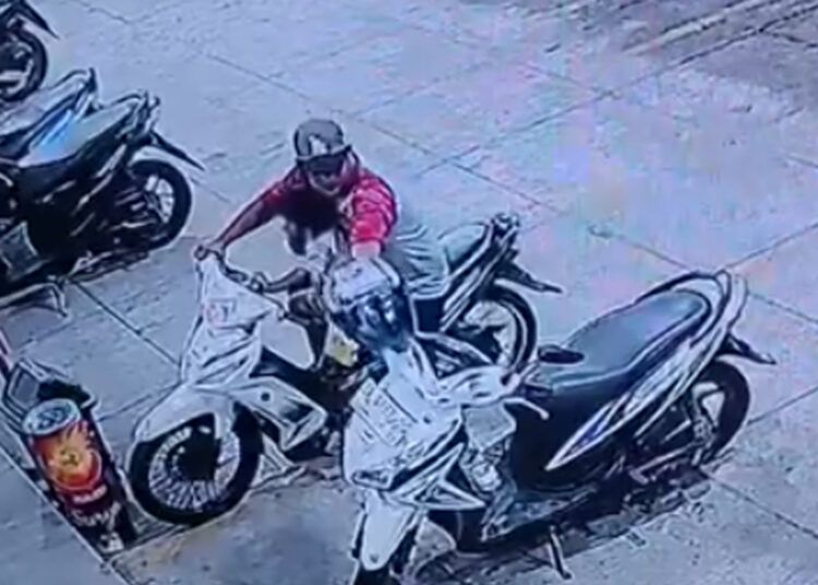 Rekaman CCTV memperlihatkan seorang pria yang membonceng anak saat diduga mengambil helm dari sepeda motor di depan Mini Market Ayang Denai, Kampung Baru, Kota Pariaman.