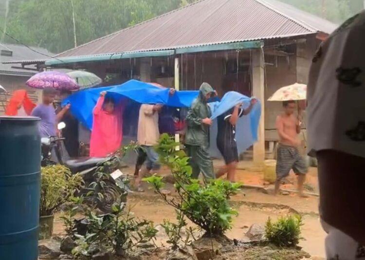 Sejumlah warga bergotong royong menandu warga yang sakit di tengah hujan di Jorong Rura Patontang, Nagari Pematang Panjang, Kecamatan Koto Balingka, Pasaman Barat.